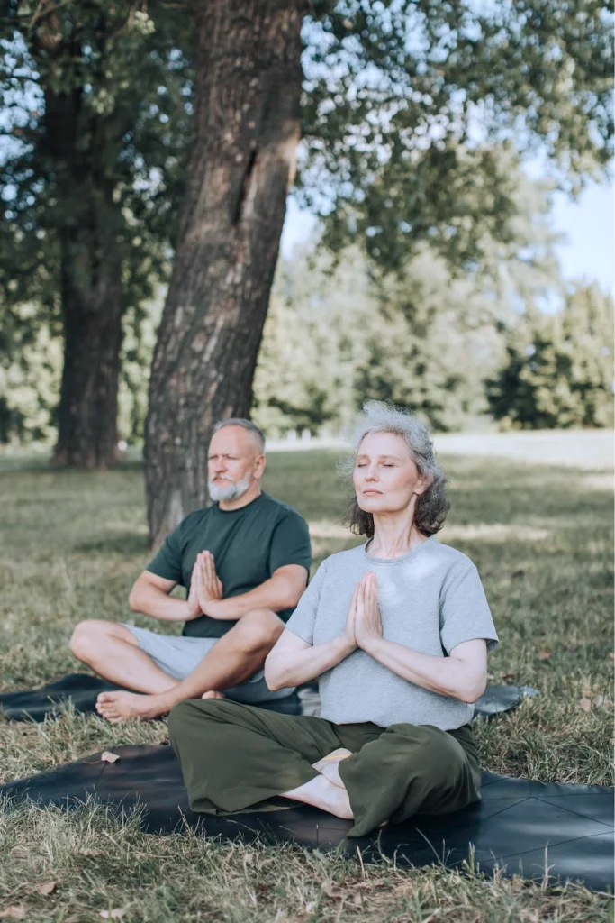 Two people meditating outdoors with their hands together